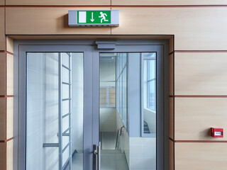 Emergency exit with glass door in airport office building. Emergency fire doors. Rescue signs icon green emergency exit lamp