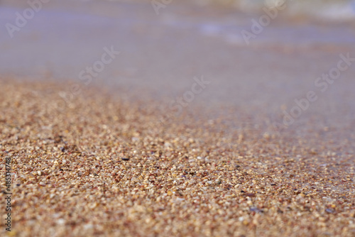Sand closeup with blurred sea on the background.