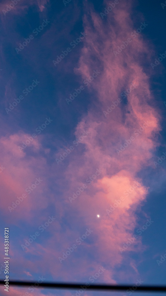 Moon behind pink clouds