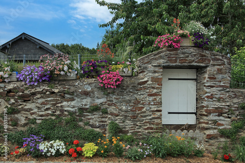 Puits fermé dans le mur d'un jardin fleuri