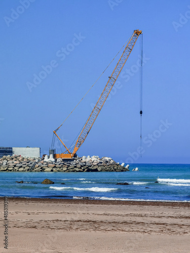 Heavy metallic machine moving rocks on the ocean in order to create a wall for the new port
 photo