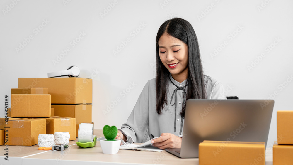 Female entrepreneur is celebrating success with arms up after checking customer order on laptop before packing Female entrepreneur is celebrating success with arms up after checking customer order on laptop before packing
