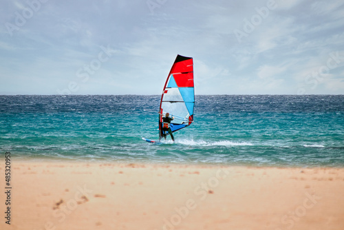 Wind surfer with red blue sail on beach of Canary Islands