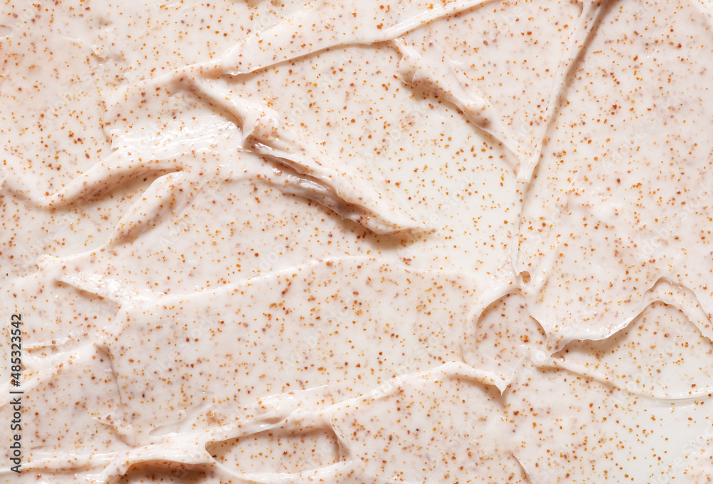 Irregular pattern of creamy organic scrub with brown grains professional skincare product as background close view from above