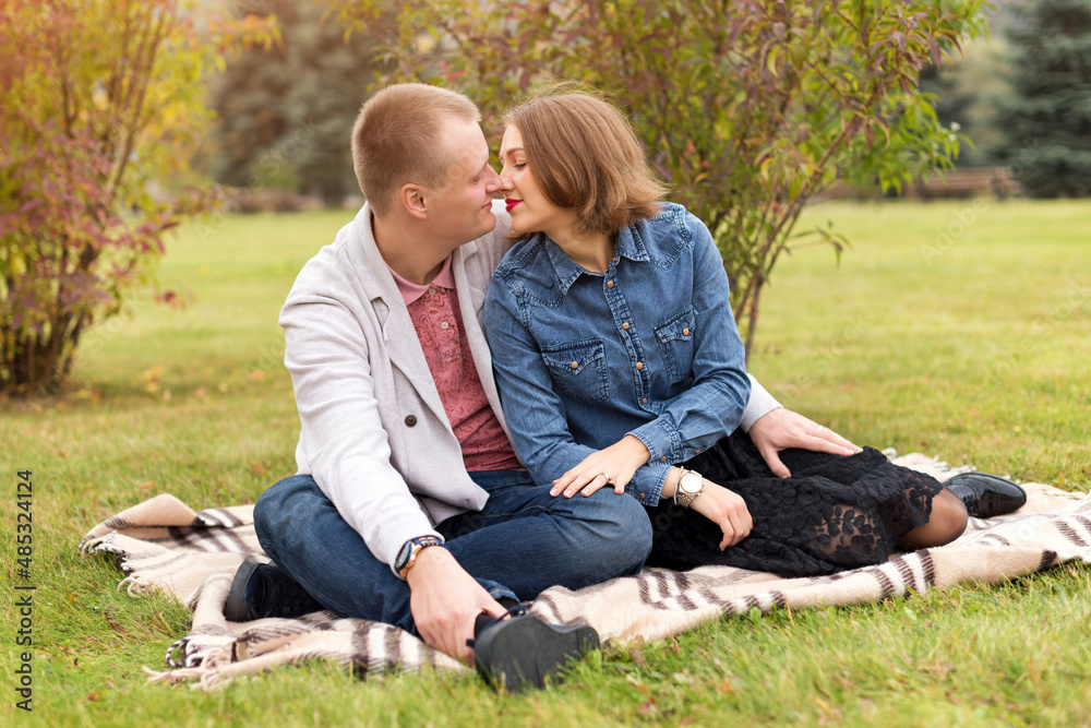Happy couple, man and woman in autumn park sitting on a plaid. Beautiful smiling couple enjoying picnic day in the park. Love and tenderness, dating, romance. Lifestyle concept. Happy couple, man and woman in autumn park sitting on a plaid. Beautiful smiling couple enjoying picnic day in the park. Love and tenderness, dating, romance. Lifestyle concept.
