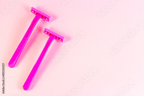 Pink disposable woman razor on light pastel background with copy space top view. Hair removing, epilation procedure and shaving concept.