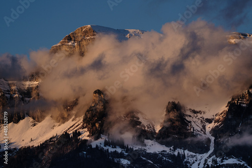 Bergkette von Wolken umgeben wird von der Sonne angeschienen. Ein nebulöses, eindrückliches Bild.