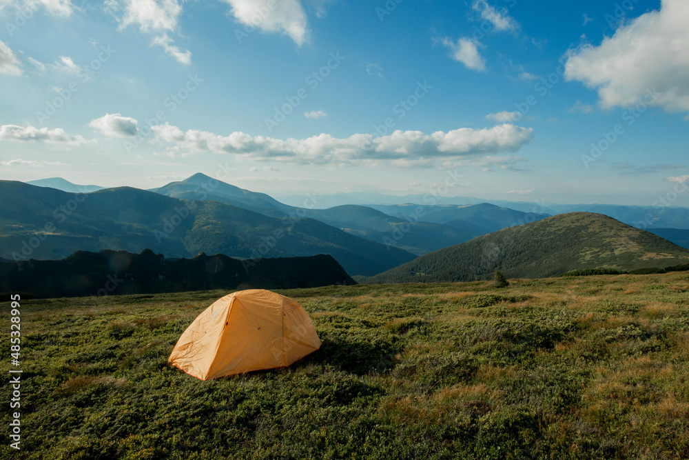 view of tourist tent in mountains at sunrise or sunset. Camping background. Adventure travel active lifestyle freedom concept. Summer vacation.