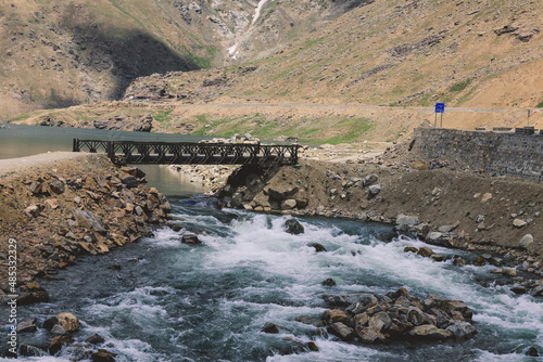 Black Bridge through the River Water Flow with Rocks in Gilgit Baltistan Highlands, Pakistan photo