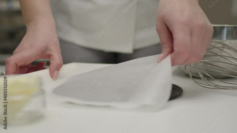 Confectioner preparing baking paper and form for cheesecake cooking. Slow motion.
