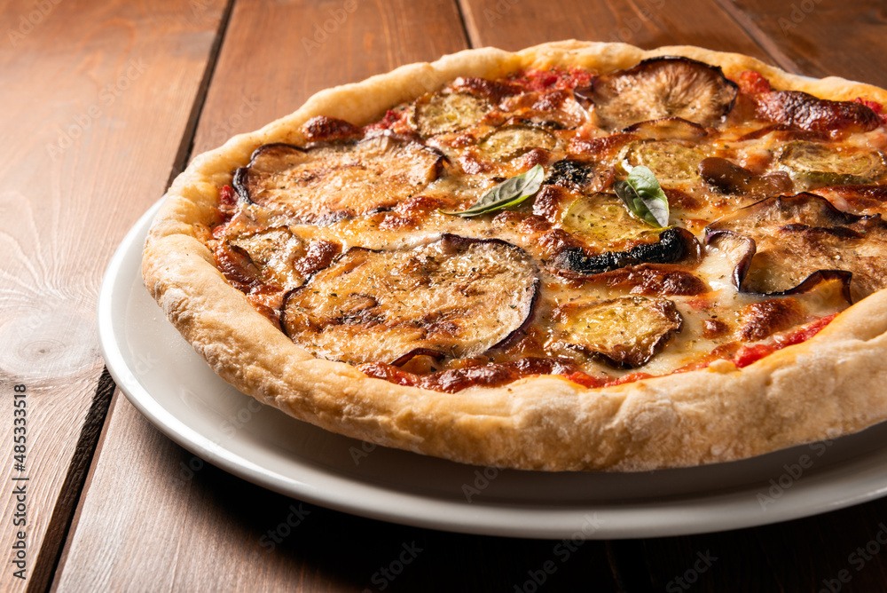 Pizza vegetariana con melanzane, zucchine e funghi su tavolo in legno 