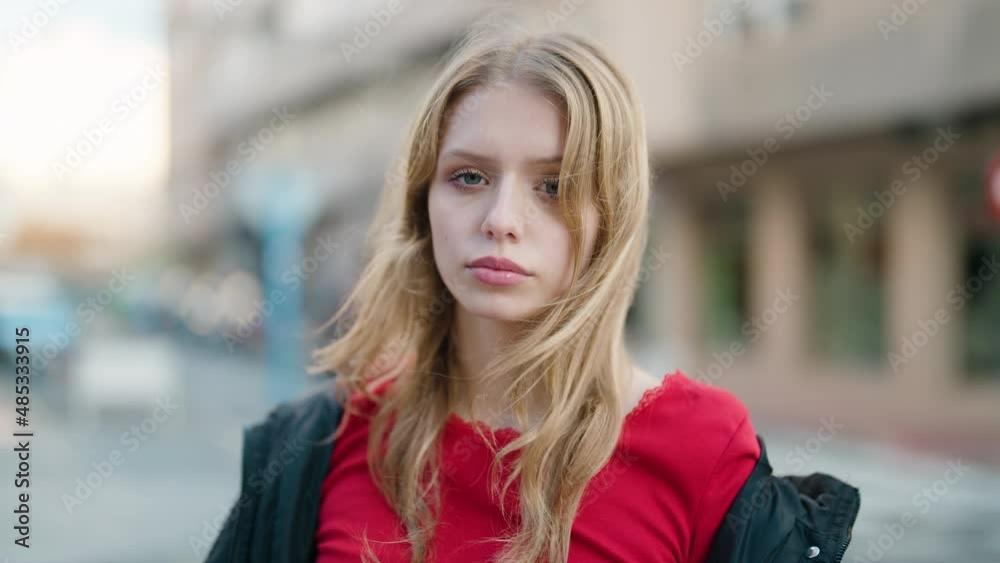 Young blonde girl with serious expression standing at street Young blonde girl with serious expression standing at street
