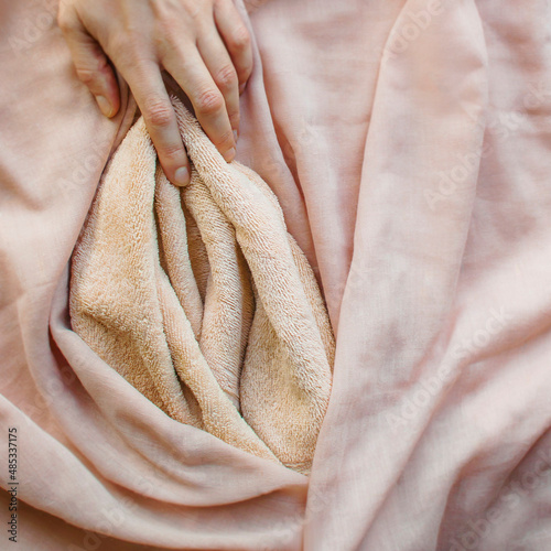 Pink soft fabric in the form of female labia and the woman's hand. One finger at the location of the clitoris. Illustration of sexual self-exploration, masturbation, relationships with vagina