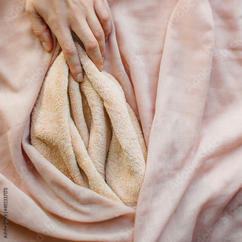 Pink soft fabric in the form of female labia and the woman's hand. One finger at the location of the clitoris. Illustration of sexual self-exploration, masturbation, relationships with vagina photo