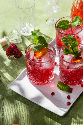 Cocktail with pomegranate juice and ice in a glass on a light green background