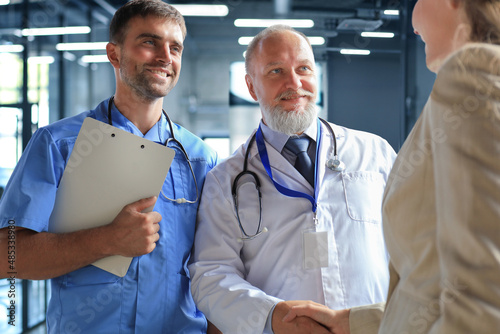 Two doctors and female patient shaking hands before consultation in the office of a modern medical center. photo