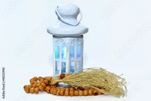 Ramadan lantern with an Islamic rosary around it isolated on a white background with a copy space for typing, selective focus of Fanoos or Lamp that commonly used in Ramadan fasting month for Muslims photo