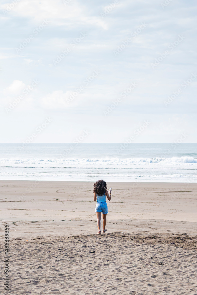 Beautiful curly-haired woman running free on the sand of a beach in Costa Rica.