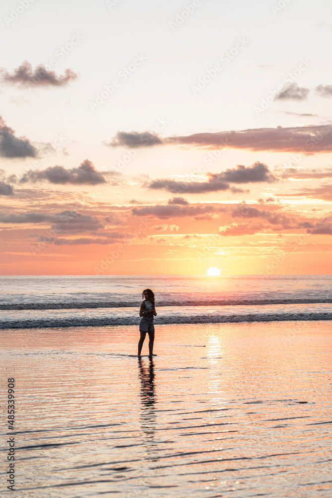 vertical portrait, Silhouette of a woman enjoying a sunset on a beach in Costa Rica.