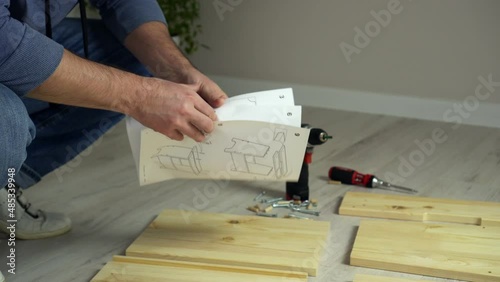 Man assembling flat pack furniture DIY at home on floor. Man assembles furniture according instructions