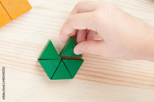 A child plays with colored blocks constructs a model on a light wooden background photo