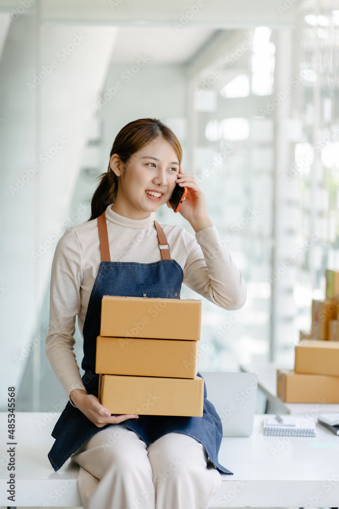 Young business woman working online e-commerce shopping at her shop. Young woman seller prepare parcel box of product for deliver to customer. Online selling, e-commerce. Young business woman working online e-commerce shopping at her shop. Young woman seller prepare parcel box of product for deliver to customer. Online selling, e-commerce.