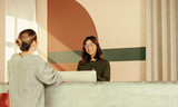 Friendly receptionist assisting a young woman at the front desk