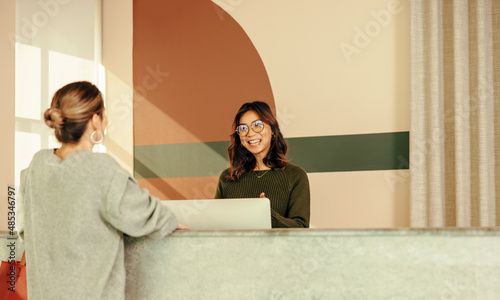 Friendly receptionist assisting a young woman at the front desk