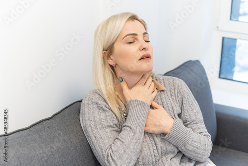 Attractive woman s sitting on bed with sore throat