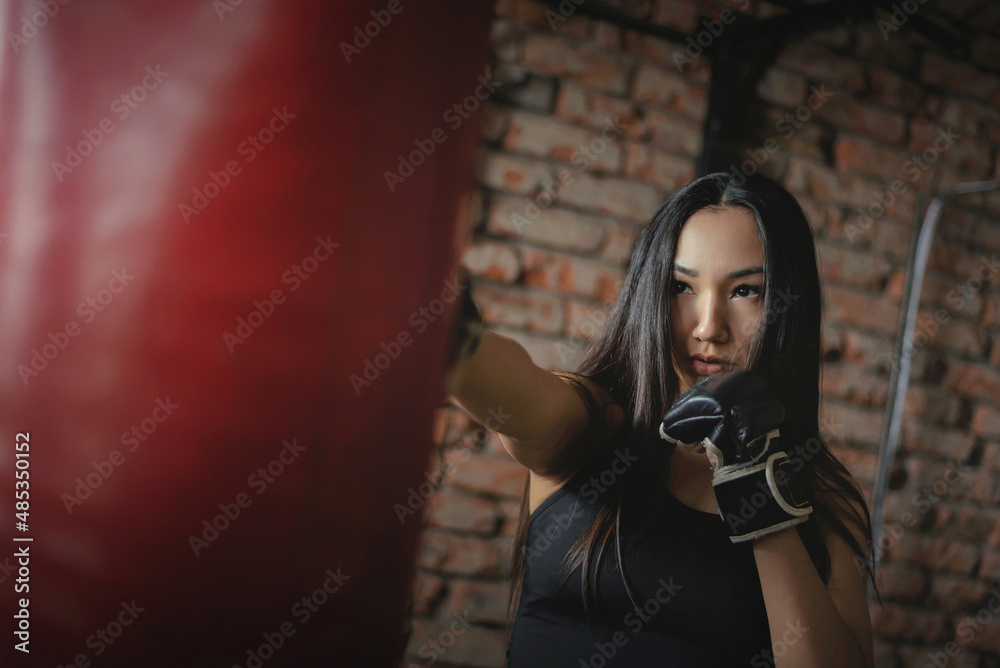 Obraz premium A girl fighter is punching a boxing bag close up concept.