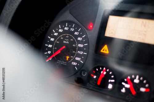 Capital T orange warning lit on speedometer of a heavy truck. Digital tachograph indicates 15 minutes left before the driver must take a brake after 4,5 hours of driving.