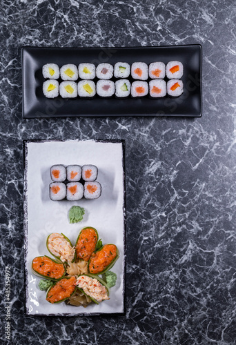 set of sushi rolls with seafood on a black stone background