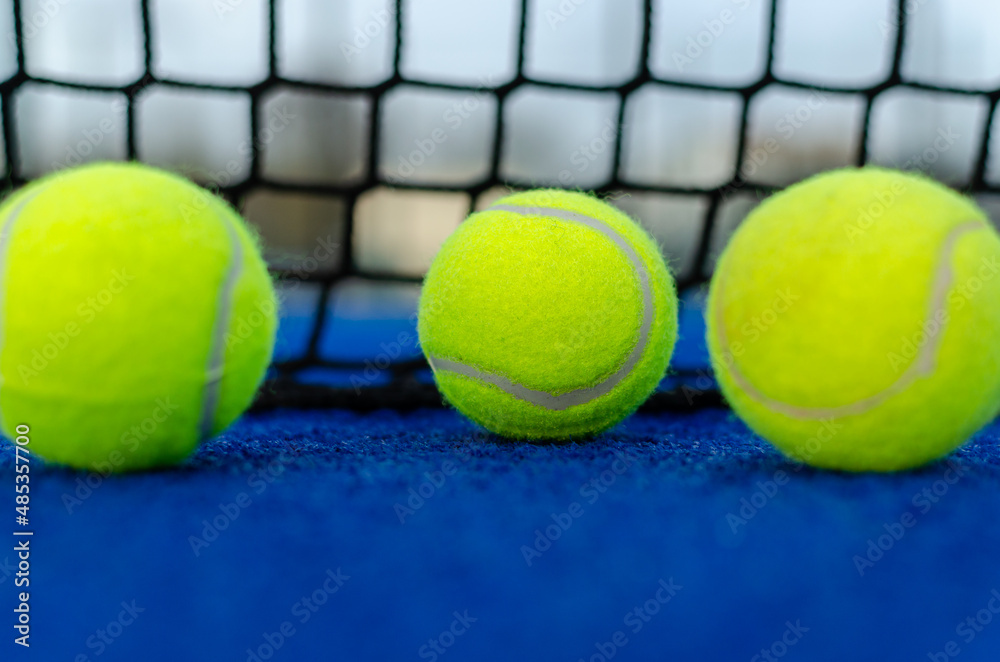 Selective focus. Three balls on a blue paddle tennis court.