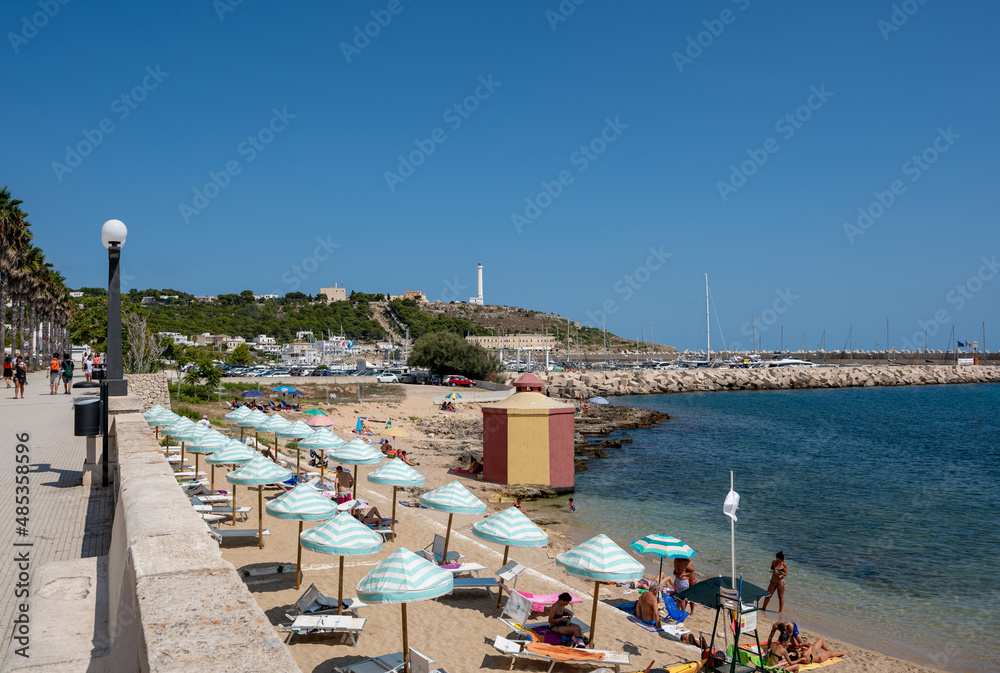 Santa Maria di Leuca, Santa Maria di Leuca, Puglia, Italy. August2021. View from the promenade along the sea on the beach with umbrellas, deck chairs and people bathing or sunbathing.