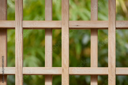 A close-up of a wooden gate with a dark green background
