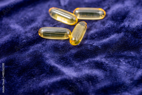Fish oil capsules on a dark blue plush cloth