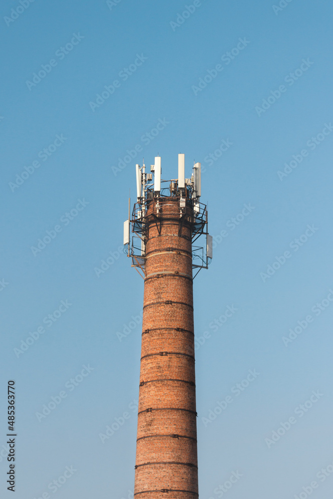 A big tall orange brick tower with lots of antennas on it. Sky background