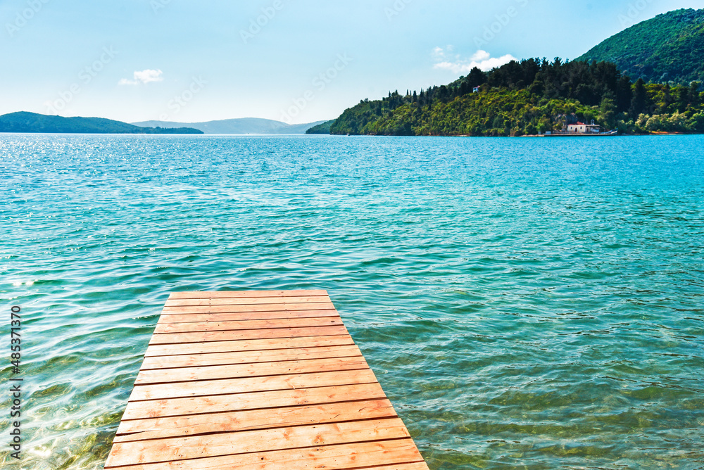 Beautiful scenic landscape with a boat in the bay and a wooden pier near Nydri, Lefkada, Greece. Stunning amazing charming places. prominent tourist towns.