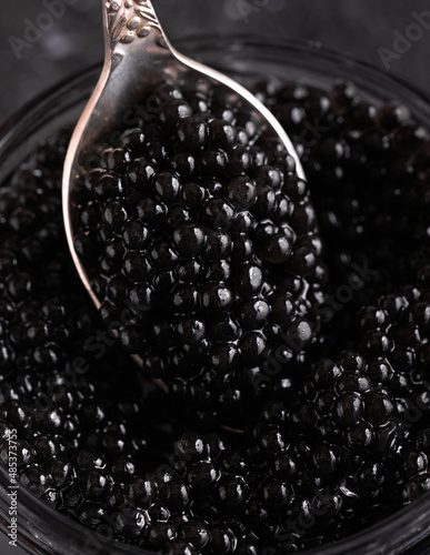 Close up vintage spoon with black caviar on dark background