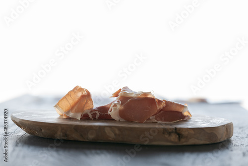 Thin slices of jamon on olive wood board