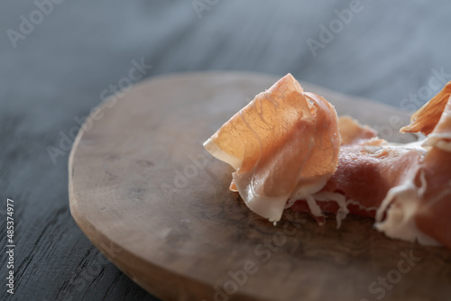 Thin slices of jamon on olive wood board