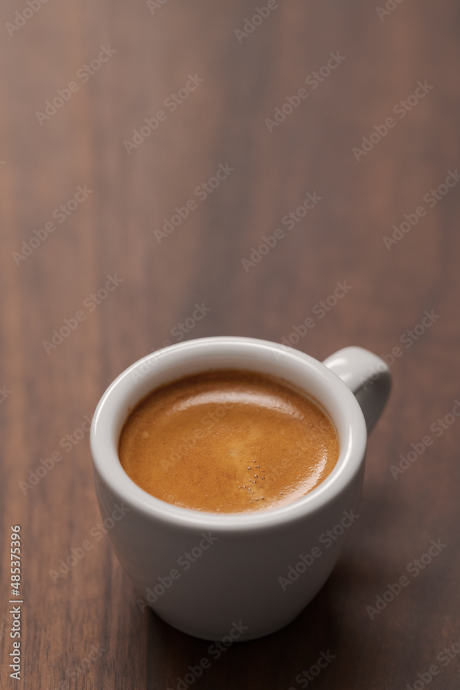 Cup of fresh espresso in white cup on walnut table with copy space Cup of fresh espresso in white cup on walnut table with copy space