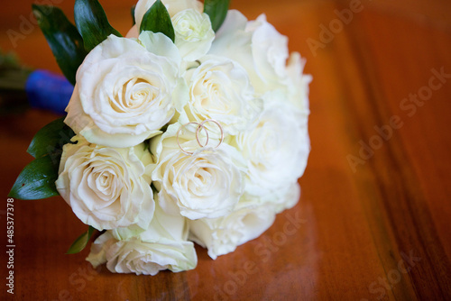 Wedding rings lie on a bouquet of roses