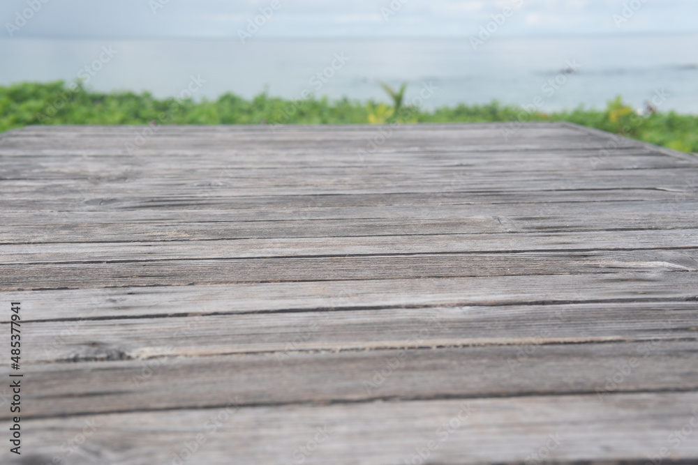 Fototapeta premium Panoramic empty clean wood counter table top blur shinny white bokeh light on summer beach background for product morning scene display montage, Abstract Blurry wooden desk in vacation trip backdrop.