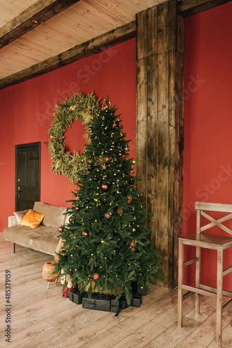 Stylish interior of the living room with a Christmas tree on a red background