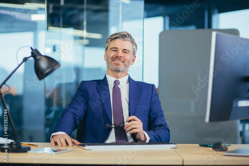 Portrait of successful seo boss, businessman at work, working on computer in modern office, looking at camera, happy and smiling © Liubomir