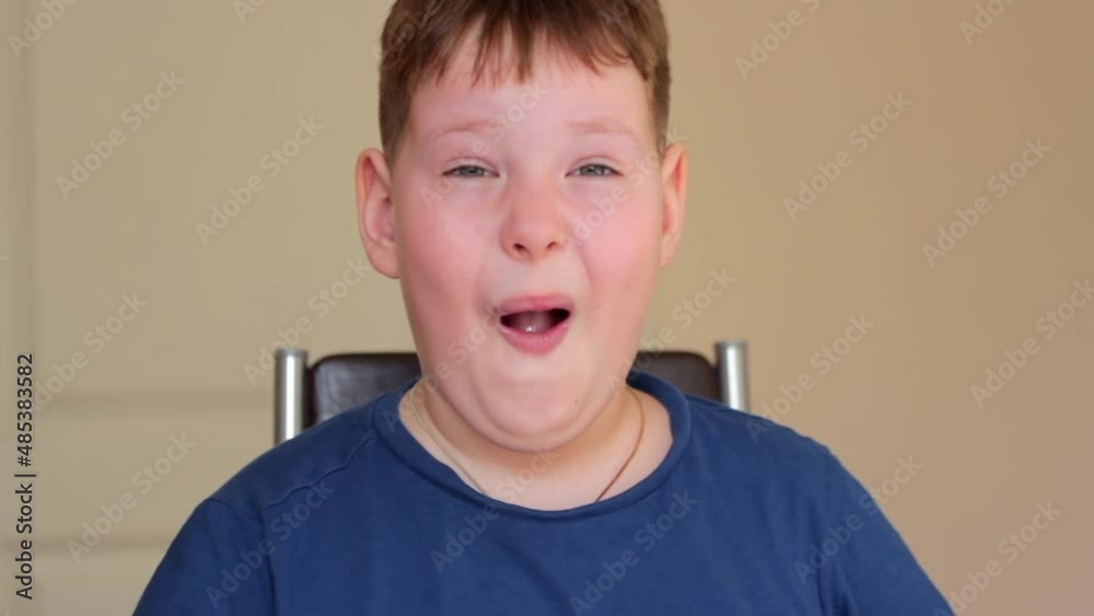 The fat boy rubs his eyes with his hands, opens his mouth in surprise. He's sitting on a chair. The fat boy rubs his eyes with his hands, opens his mouth in surprise. He's sitting on a chair.