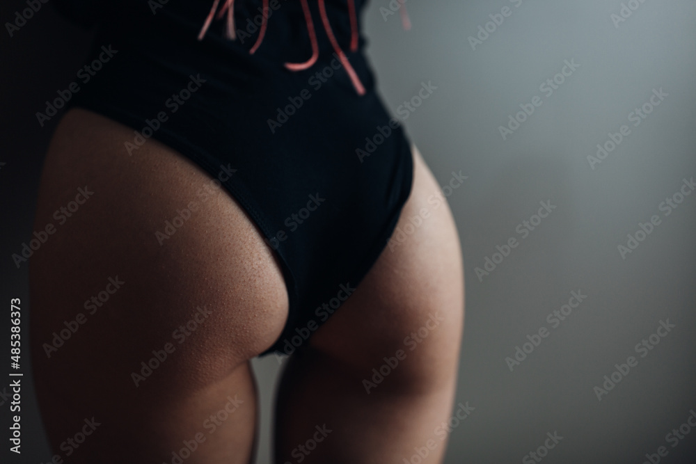 Fototapeta premium Beauty woman with attractive buttocks in black lingerie near the wall