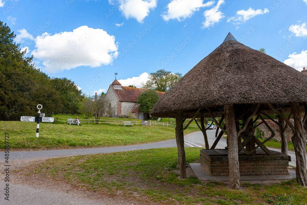 A typical English village: East Marden, West Sussex, UK, in the heart of the South Downs National Park, with a thatched-roofed well on the village green and the 12th century St. Peter's church beyond A typical English village: East Marden, West Sussex, UK, in the heart of the South Downs National Park, with a thatched-roofed well on the village green and the 12th century St. Peter's church beyond