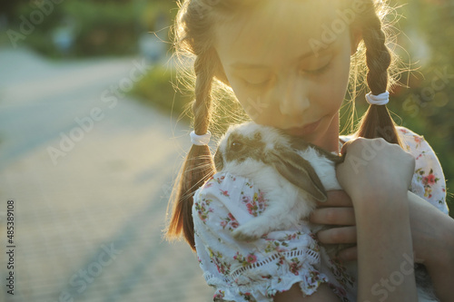 Girl hugging baby rabbit outdoors
